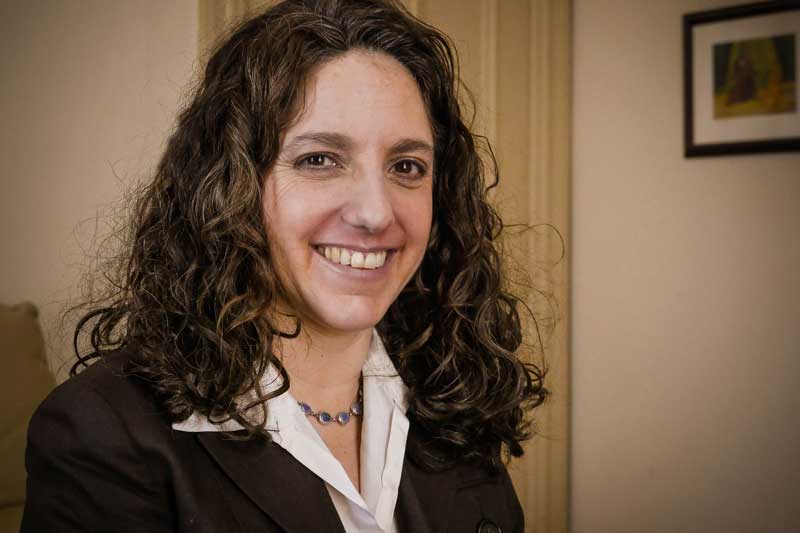 A woman with long curly hair wearing a suit.